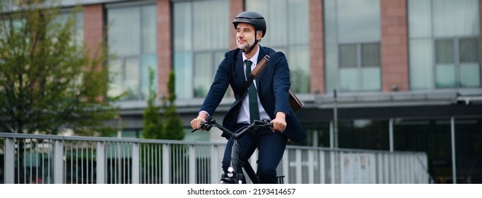 Businessman commuter on the way to work, riding bike in city, sustainable lifestyle concept. Wide photography.