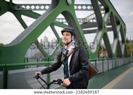 Businessman commuter on the way to work, riding bike over bridge, sustainable lifestyle concept.