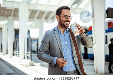 Businessman commuting in the city. Business person is waiting for train and drinking coffee. Bearded male is waiting for a train on a station. Business man with suit holding the coffee cup at station - Powered by Shutterstock