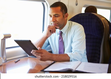 Businessman Commuting On Train Using Digital Tablet