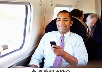 Businessman Commuting To Work On Train Using Mobile Phone