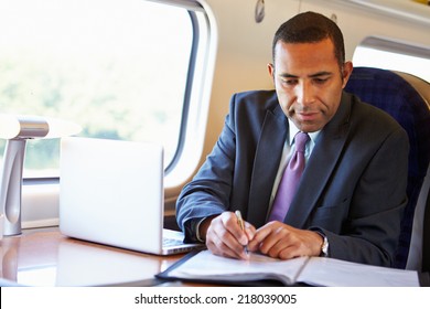 Businessman Commuting To Work On Train And Using Laptop