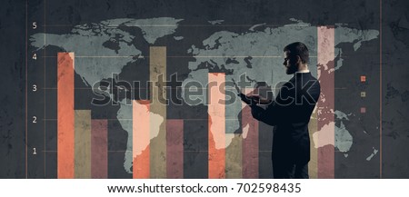 Businessman with computer tablet standing over diagram. World map background. Business, globalization, capitalism concept. 