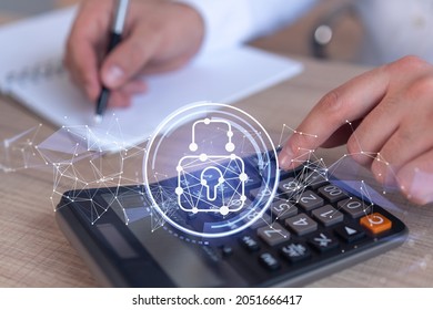 A businessman computing probability of risks in cyber security protection using calculator. Padlock Hologram icons over the working desk. Formal wear.