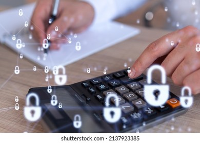 A businessman computing probability of risks in cyber security protection using calculator. Padlock Hologram icons over the working desk. Formal wear.