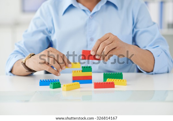 Businessman connecting lego details at his place of work