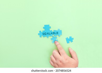 Businessman connecting puzzle pieces with the word Scalable. Scalability concept image.