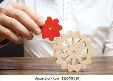 Businessman connects a small red gear to a large gear wheel. Symbolism of establishing business processes and communication. Increase efficiency and productivity. The best business formula for success