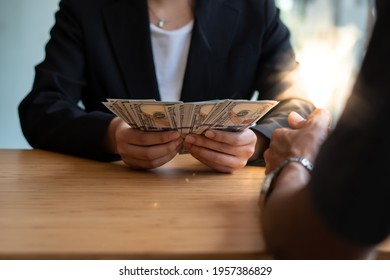 The businessman considers cash dollars in the office issues salaries to employees with black cash divides the profits as a result of illegal transactions everyone is happy. - Shutterstock ID 1957386829