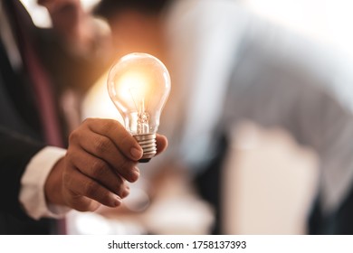 Businessman controls a light bulb floating by hand, new ideas with innovative technology and creativity,concept difficult job 

