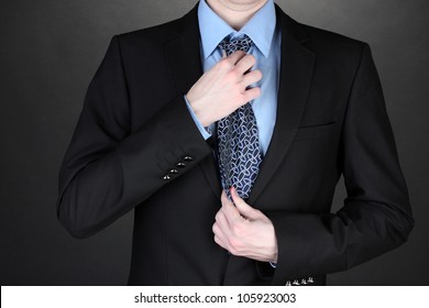 businessman correcting a tie on black background