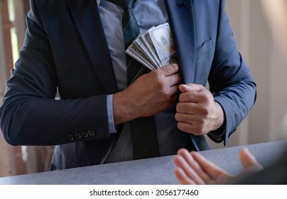 businessman or corrupt politician is offering bribes that are given in the form of dollar cash To do illegal business, corruption in the contracting business, corruption concept and bribery. - Shutterstock ID 2056177460