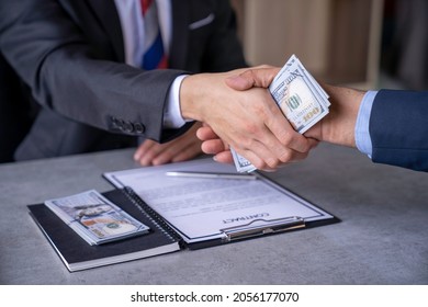 businessman or corrupt politician and willing to accept bribes given in dollar cash To do illegal business, corruption in the contracting business, corruption concept and bribery. - Shutterstock ID 2056177070