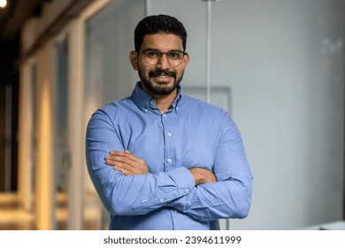 Businessman with crossed arms smiling and looking at camera, portrait of happy male worker inside office, boss in glasses and shirt, happy with achievement results, proud and confident. - Shutterstock ID 2394611999