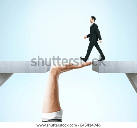Businessman crossing abstract hand bridge on blue background. Teamwork concept