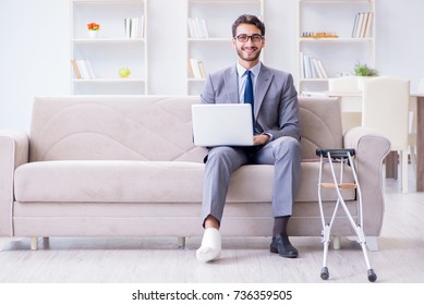 Businessman With Crutches And Broken Leg At Home Working