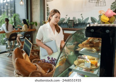 Businessman customer, beautiful Asian woman cream colored shirt holding laptop Standing bakery  baguette Intentionally displayed front bakery freezer inside small business cafe Minimalist style shop - Powered by Shutterstock