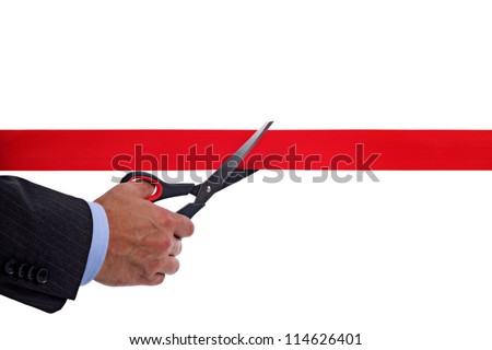Businessman cutting a red ribbon with a pair of scissors