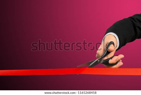 Businessman\
cutting red ribbon with pair of\
scissors