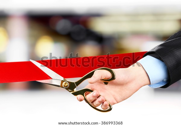 Businessman cutting red ribbon with pair of scissors\
close up