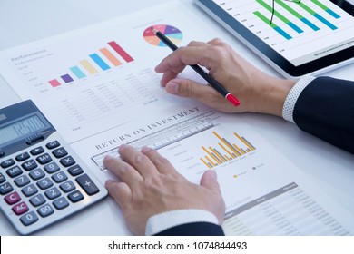 Businessman is deeply reviewing a financial report for a return on investment or investment risk analysis. - Shutterstock ID 1074844493