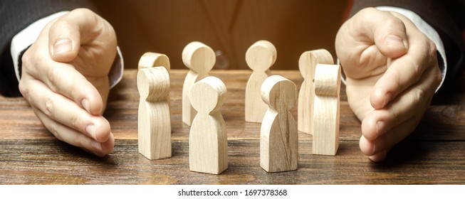 Businessman defending his team with a gesture of protection. Care for employees. Life insurance. Security and safety in a business team. Human resources. Social protection. Wooden figures