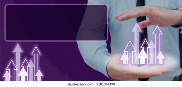 Businessman With Digitally Generated Arrows Moving Up In Hands By Digital Framework. Man Wearing Necktie Analyzing Data And Showing Business Achievements.