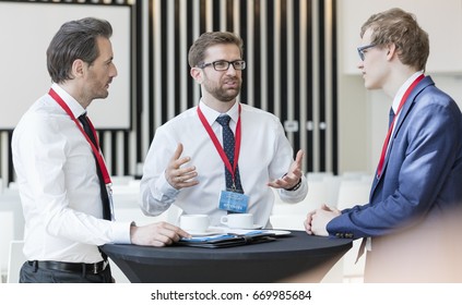 Businessman discussing with colleagues during coffee break in convention center - Powered by Shutterstock