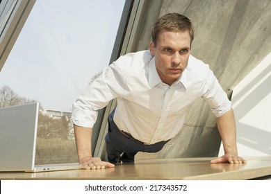 Businessman doing push-ups in the office - Powered by Shutterstock