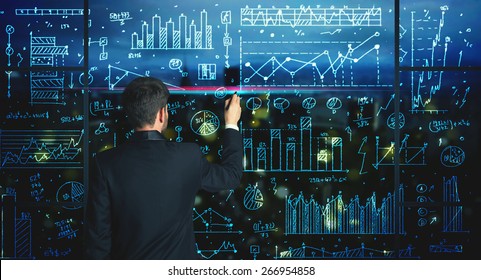 Businessman Drawing Business Statistics On Glass Wall