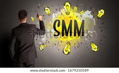 businessman drawing colorful light bulb with SMM abbreviation, new technology idea concept