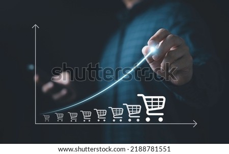 Businessman drawing increasing trend graph of sale volume with bigger shopping trolley cart for  online sale business growth concept.