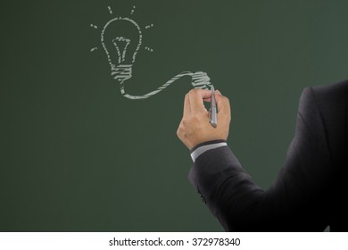 Businessman Drawing Light Bulb On Board. Light Bulb Idea For Inspiration Creative