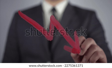 Businessman draws a graph of negative market growth. A man in a suit draws on glass with a brush and red paint.