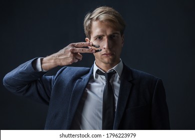 Businessman Draws Two Stripes On His Cheeks, War Paint. Competition In Business, Concept. A Young Man In A Suit And Tie Makes War Paint On His Face