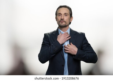 Businessman is dressing up and adjusting tie on his neck. Mature middle-aged handsome man is getting ready for important meeting. Bright blurred background. - Powered by Shutterstock