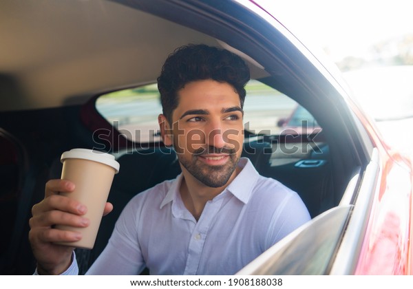 Businessman drinking coffee in\
car.