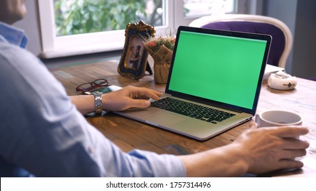 Businessman drinking coffee in his office and reading something on the computer.Shot of a man typing on a computer laptop with a key-green screen. Man hand typing laptop with green screen.
 - Powered by Shutterstock