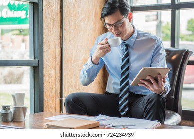 Businessman drinking coffee and holding tablet while reading document before work in the morning. - Powered by Shutterstock