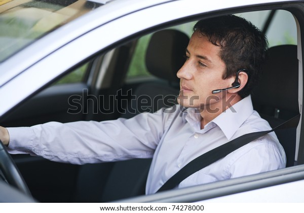 Businessman\
driving a car with blue-tooth\
hands-free