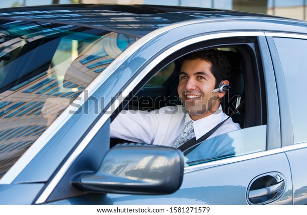 Businessman driving car using hands free mobile
phone earpiece