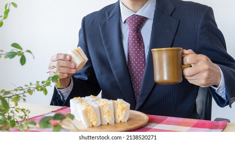 A businessman eating a sandwich. Egg salad sandwich and coffee. - Powered by Shutterstock