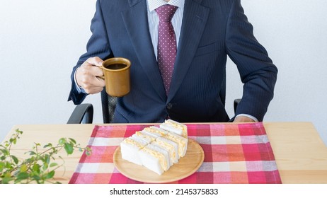 A Businessman Eating A Sandwich. Egg Salad Sandwich And Coffee.