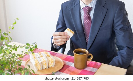 A Businessman Eating A Sandwich. Egg Salad Sandwich And Coffee.