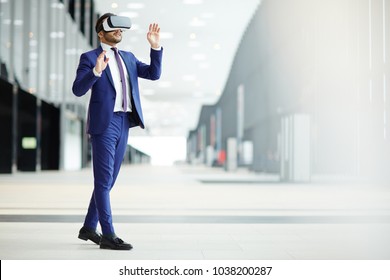 Businessman in elegant blue suit and vr headset taking part in virtual conference while moving inside modern building - Powered by Shutterstock