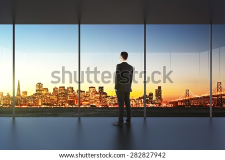 Businessman in empty office looking at beautiful skyline