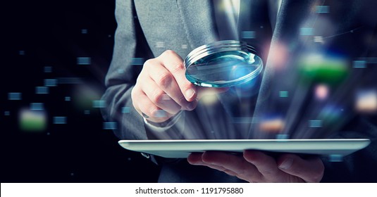 Businessman examines a tablet with a magnifying glass. Concept of internet security