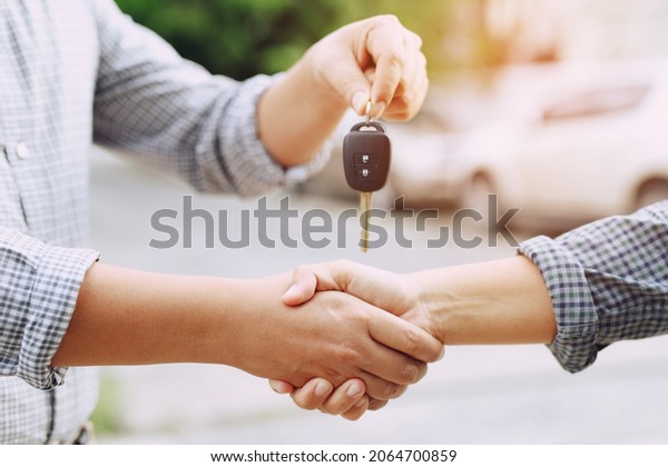 businessman exchange handing over the car keys for\
to a young women.