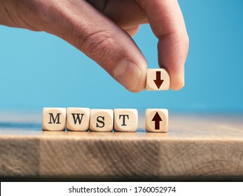 A businessman exchanges a wooden cube with an up arrow for a wooden cube with an down arrow. German economic stimulus package with VAT reduction. - Shutterstock ID 1760052974
