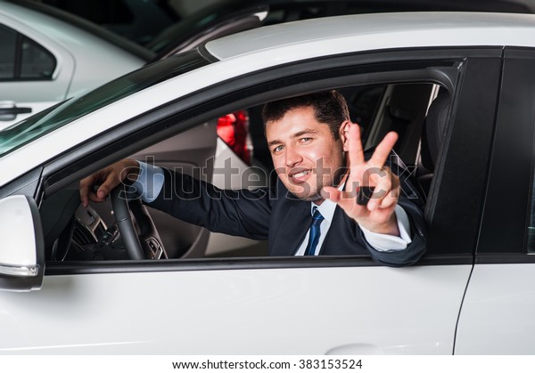 Businessman  excited about his new vehicle.\
Positive face\
expression